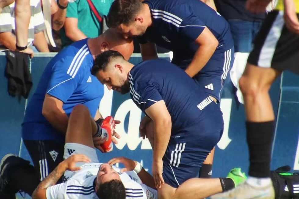Fisioterapeutas atendiendo a un jugador sobre el terreno de juego durante un partido