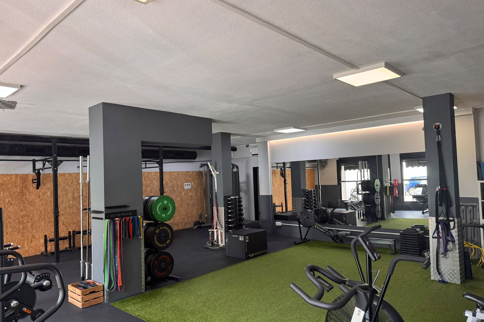 Sala de entrenamiento y readaptación con racks, discos y zona de césped